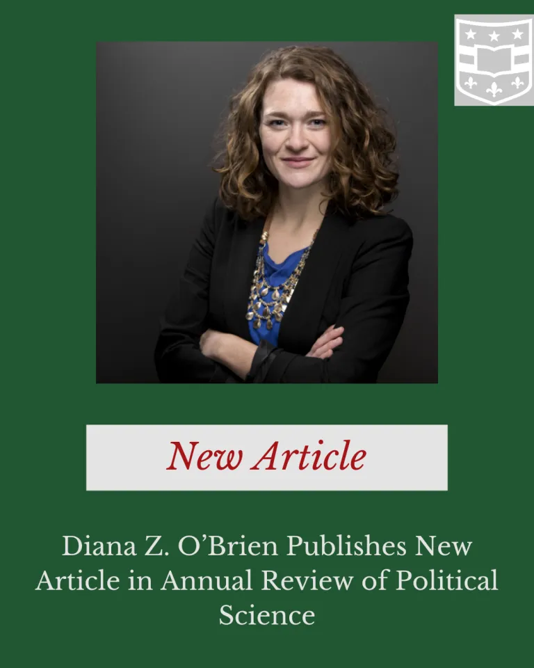 Photo of Diana Z. O'Brien smiling and looking at the camera in a blue and gold top and dark blazer with her arms crossed at her chest.