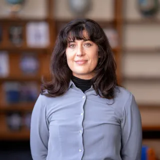 Photo of Amanda Nutter in a library smiling with a blue button up top