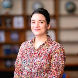 Photo of Mariah Pugliese in a library smiling in a multi-colored top